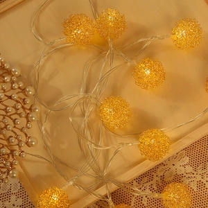 Guirlande lumineuse LED boules dorées en métal ajouré sur plateau décoratif