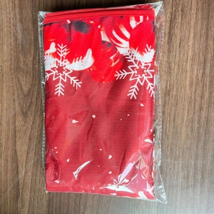 Folded red Christmas tree skirt with white snowflake patterns in plastic packaging