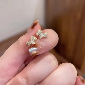 Gold plated horse stud earrings with cubic zirconia stones shown on hand for size
