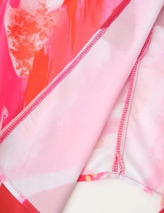 Détail du tissu plissé avec imprimé abstrait rose et orange et coutures de précision