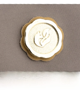 Close-up of golden circular metal logo featuring a fox emblem on textured nylon fabric