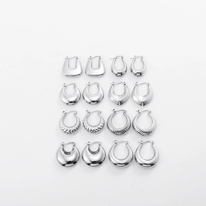 Flat lay of diverse silver hollow hoop earrings in various textured and smooth U-shaped designs