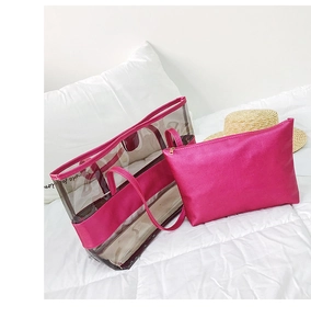 Clear PVC beach tote bag with magenta pouch shown on white bedding with a straw hat