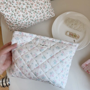 Détail de la trousse de maquillage matelassée en coton fleuri avec étiquette décorative