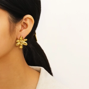 Minimalist golden flower stud earrings for women shown worn on a model's ear