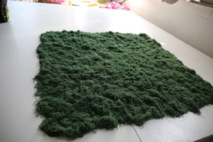 Close-up of thick artificial moss turf with high-density flocked green fiber texture