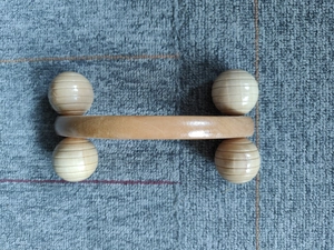 Details eines Holz-Massagerollers mit vier Kugeln auf einem grauen Handtuch
