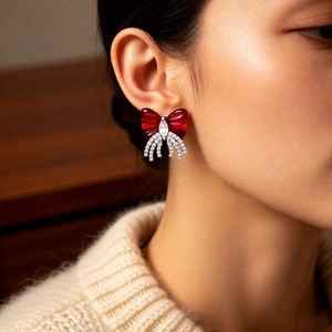 Detail of red bow earring with zircon tassels worn on ear to show size and luxury look