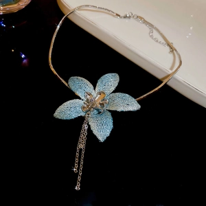 Detail of a blue fabric flower pendant with silver tassels and sleek snake chain