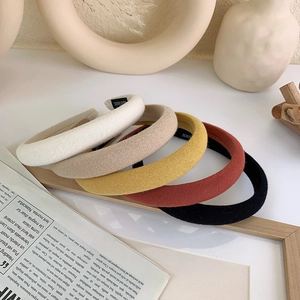 Minimalist fabric padded headbands in cream tones arranged on a wooden tray