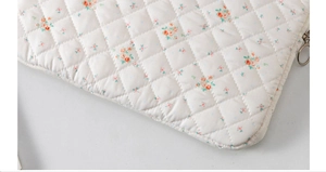 Close-up of quilted floral pattern and metal ring zipper on the padded laptop sleeve