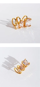 Macro shot of three graduated gold ear cuffs with square zircon stones and rainbow light reflections