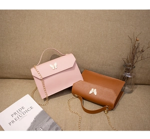 Detailed close-up of pink and brown crossbody bags with butterfly buckle on fabric background