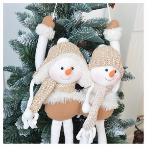 Close-up of plush snowman ornaments with knit hats hanging on a Christmas tree branch