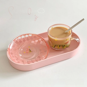 Close-up of a pink glass coffee cup set with flower patterns and a checkered saucer