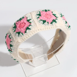 Close-up of hand-knitted beige headband featuring pink and green floral embroidery details