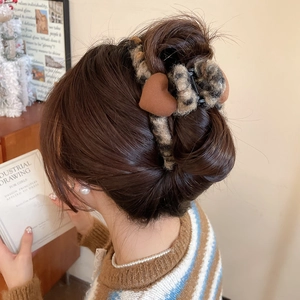 Détail d'une pince à cheveux en peluche léopard avec un motif de cœur décoratif