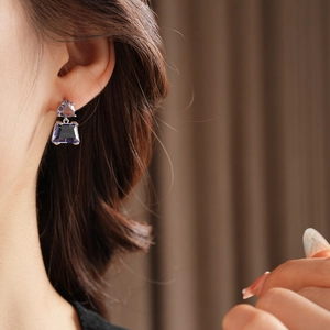 Detail of silver earring featuring purple triangle and trapezoid cut cubic zirconia