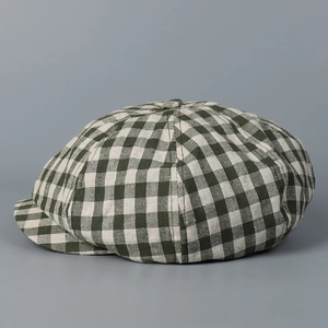 Detailed view of the dark green and beige gingham textured linen newsboy cap with top button
