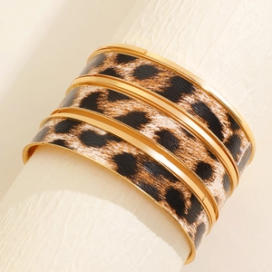 Macro shot of wide gold-toned leopard print cuff bracelet with textured animal patterns