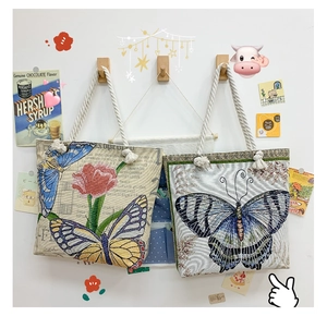 Detailed embroidery of flowers and butterflies on canvas tote with cotton rope handles