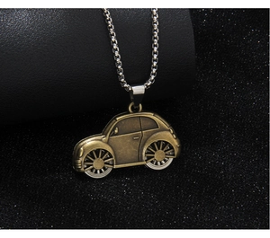 Macro detail of retro bronze-tone car pendant on silver chain against a dark backdrop