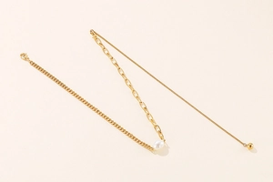 Detail of gold titanium steel necklace with white pearl and mixed chain link textures