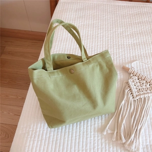 Detail of light green canvas tote bag showing magnetic metal clasp and stitching