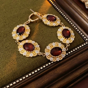 Vintage gold bracelet with oval deep red gemstones and white floral enamel details