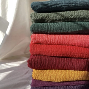 Stack of colorful crinkle cotton scarves in various vibrant tones with rich pleated texture