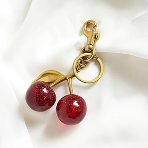 Porte-clés cerise rouge étincelant avec fermoir doré sur fond de tissu blanc élégant