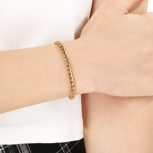 Gros plan d'un bracelet gourmette tressé en or élégant porté au poignet pour femme
