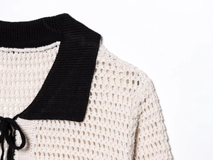 Detail of crochet polo cardigan featuring cream knit texture and black contrast collar