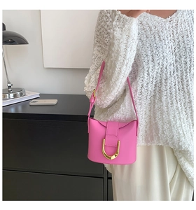 Chic pink handbag detail with a large gold U-shaped metal buckle and matte leather texture