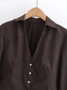 Detail shot of a dark coffee striped blazer with white buttons on a wooden hanger