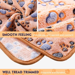 Close-up of soft coral fleece pet blanket with blue paw prints and durable stitching