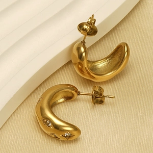 Detailed view of gold C-shaped earrings with diamond accents and textured inner surface