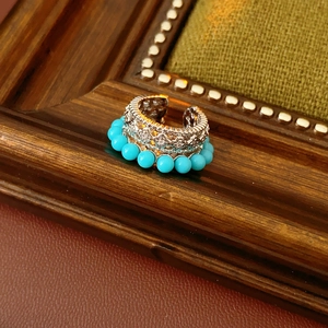 Dettaglio di orecchini vintage in argento con perle di turchese su cornice in legno