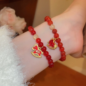 Détail de bracelets en perles d'agate rouge avec pendentifs cheval à bascule dorés
