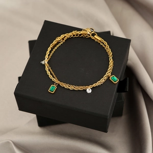 Close-up of double-layer gold titanium bracelet with green gemstone on black gift box