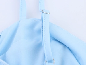 Detail of light blue dress shoulder strap with adjustable metal buckle and textured fabric