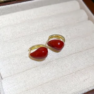 Vintage gold waterdrop earrings with red enamel inlay on soft velvet display tray