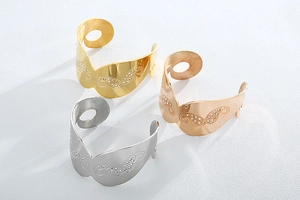 Close-up of gold, rose gold and silver open cuff bracelets with rhinestone butterfly motifs
