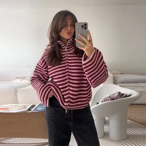 Dettaglio del maglione a righe rosa e bordeaux con doppia cerniera e colletto a polo