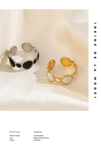 Detail of adjustable geometric rings with black enamel and white shell on silk background