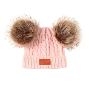 Pink knit baby beanie with double faux fur pom poms and twisted cable texture