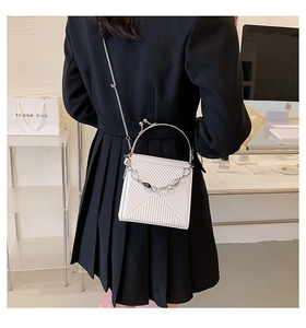 Detailed back view of a white geometric textured bag with metal chain strap