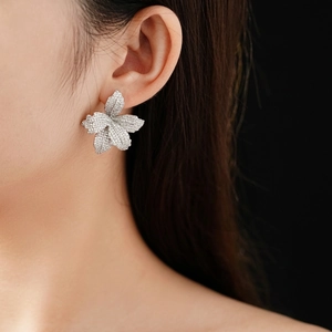 Elegant silver flower stud earrings with shimmering cubic zirconia on a female model