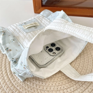 Macro view of floral quilted handbag interior showing snap button and phone storage