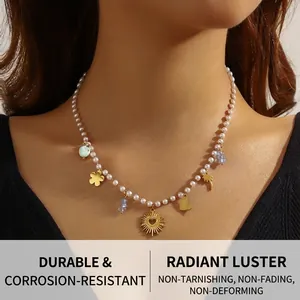 Nahaufnahme einer Perlenkette mit goldenen Herz-, Palmen- und Blumenanhängern am Model